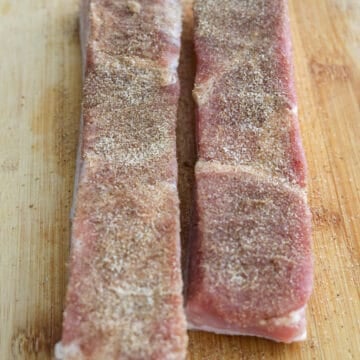 Turn the pork belly meat side up and evenly season with the dry rub mixture patting it into the meat. 