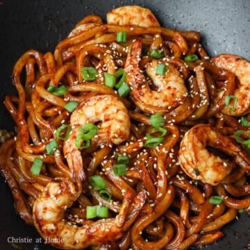 Then toss in the cooked shrimp with the noodles. Remove off heat. Garnish with sesame seeds and more green onions. Enjoy!