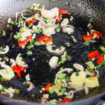 In the same pan, reduce to medium heat, add remaining oil.  Sauté red chili, green onions, shallot, garlic and ginger for 15 seconds. 