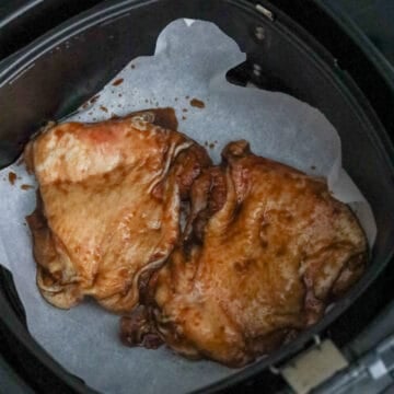 Lightly spray the air fryer basket with vegetable oil or cooking spray or line the base of the basket with air fryer parchment paper. Place chicken thighs in the basket in a flat single layer and skin side up. You will need to air fry in batches depending on the size of your air fryer. 