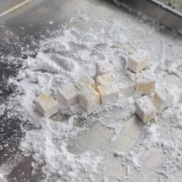 Spread cornstarch on a large plate or baking sheet. Evenly coat tofu cubes in cornstarch in batches using clean hands (do not simply dump the cornstarch over all the tofu and mix or they won't coat properly). Transfer coated tofu into a large bowl. 