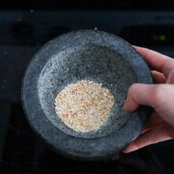 Transfer toasted rice into a mortar and pestle, spice grinder or a high power blender. Grind the rice until it becomes toasted rice powder.