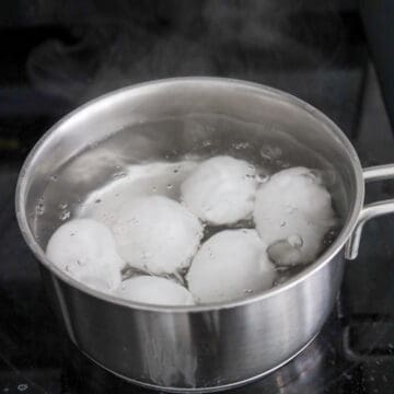 Bring a small pot of water to boil on medium-high heat and add salt and vinegar. Gently lower in room temperature eggs and reduce to medium heat for a rolling boil. Do not cover. Set a timer and soft boil for 6.5 mins or 10 minutes for hard-boiled eggs. 