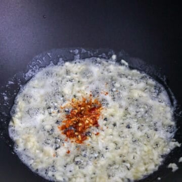 Once butter has melted, add minced garlic and fry for 10 seconds. Then stir in red chili flakes for 5 seconds.