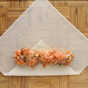 Gently peel away one single spring roll wrapper and place onto a clean flat surface. Fold the bottom corner ⅓ of the way up. Fill the wrapper with 3 levelled tablespoons of filling and shape them into a log.
