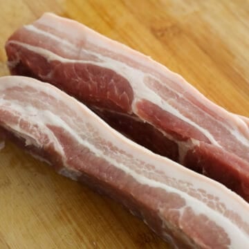 Pre-heat the oven to 225 degrees F. If needed, cut boneless pork belly lengthwise into 2-inch wide x 9-long strips. Trim off any uneven meat from the bottom to create a levelled strip. Pluck out any hairs on the skin with clean tweezers.