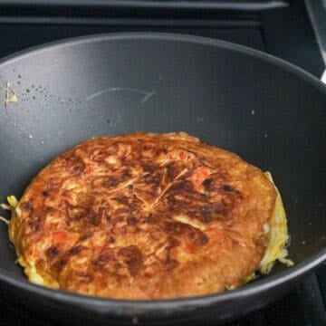 Fry omelet on the first side for 3 minutes until the bottom is golden brown and crispy. Flip over with a large spatula and fry on the other side for 2 mins, until golden and crispy. Remove and transfer omelet to serving plate. 