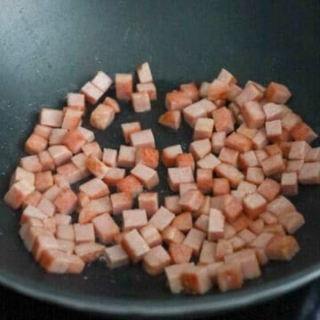 Dice spam into small cubes, about 1 cm x 1 cm. Heat vegetable oil in a large pan on medium-high heat. Fry diced spam for 2-3 minutes or until lightly golden brown on the edges. Remove and set aside. 