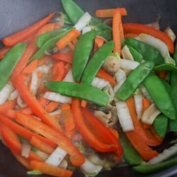 In a large skillet or large wok, on medium-high heat, heat vegetable oil. Add carrots, red bell pepper, snow peas, mushrooms and napa cabbage. Add ¼ cup or 60 ml cold water to help cook and soften the vegetables. Cook for 1-2 minutes until the water in the pan has evaporated. 