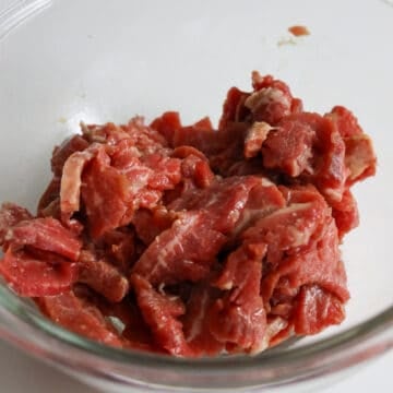 Thinly slice flank steak against the grain into ¼-inch-thick pieces. Transfer beef slices to a large bowl.  Add marinade ingredients to the beef and mix well. Marinate for 15 minutes. (Tip: To thinly slice beef, freeze flank steak uncovered for 45-60 minutes until the exterior is hard and use a sharp knife).