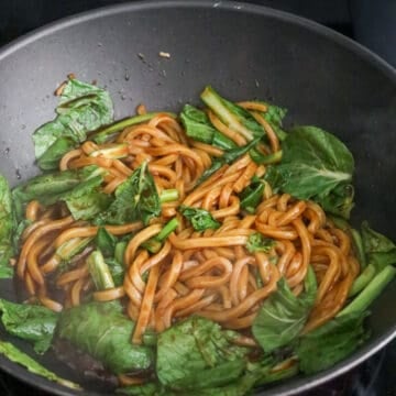 Increase to medium-high heat, add udon noodles with noodle sauce. Mix well and cook until sauce has slightly thickened and isn’t so runny. Toss in greens and cook until they’re softened. 