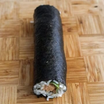 Begin rolling the kimbap by starting at the end closest to you. Firmly roll and tuck the ingredients and be careful not to squeeze the tuna filling out as you roll. Once you reach the end, let the roll sit on top where the border was so it can stick to the rest of the roll with the residual heat from the rice. 