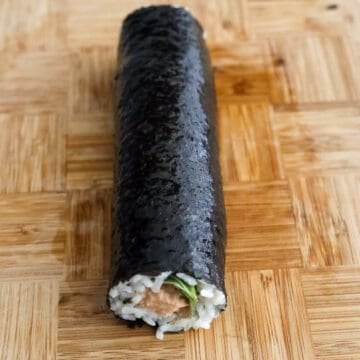 Then evenly pour ½ teaspoon sesame oil on the kimbap roll and with clean hands or a brush, spread it all over the seaweed. Repeat the above steps for the remaining roll. 