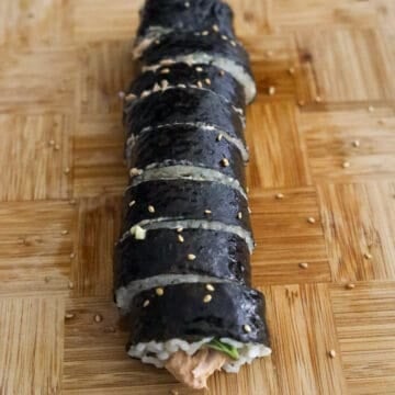 Sliced 1-inch pieces of kimbap coated with sesame oil and garnished with sesame seeds.