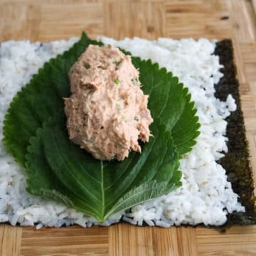 Scoop half of the spicy tuna mixture on top of the perilla leaves and evenly shape the tuna mixture into a thick log. Do not spread it out thinly or when you roll it, the tuna filling will spill out from the sides. The tuna filling will eventually spread out evenly with enough rolling pressure. 