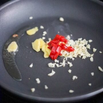 Discard excess oil leaving 1 teaspoon in the pan and on low heat saute garlic, chilies and ginger