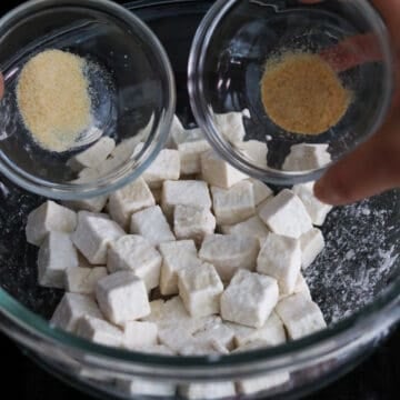 Season coated tofu with garlic powder and onion powder by gently mixing with hands.