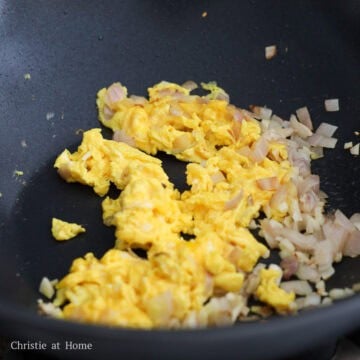 Sauté shallots and garlic for 10 seconds, until fragrant and push to the side. Add remaining oil into the empty space. Then add beaten eggs and let them sit for 10 seconds before scrambling and breaking into bite-sized pieces. Push to the side.