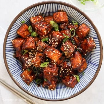 Toss fried tofu in the thickened sauce until evenly coated. Remove off heat. Garnish with green onions and sesame seeds. Enjoy!