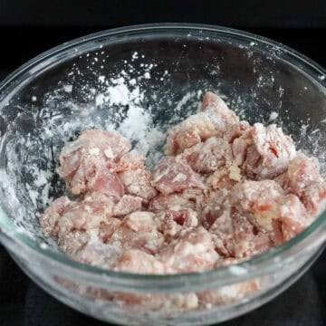 Coat diced chicken thighs in cornstarch until evenly coated.