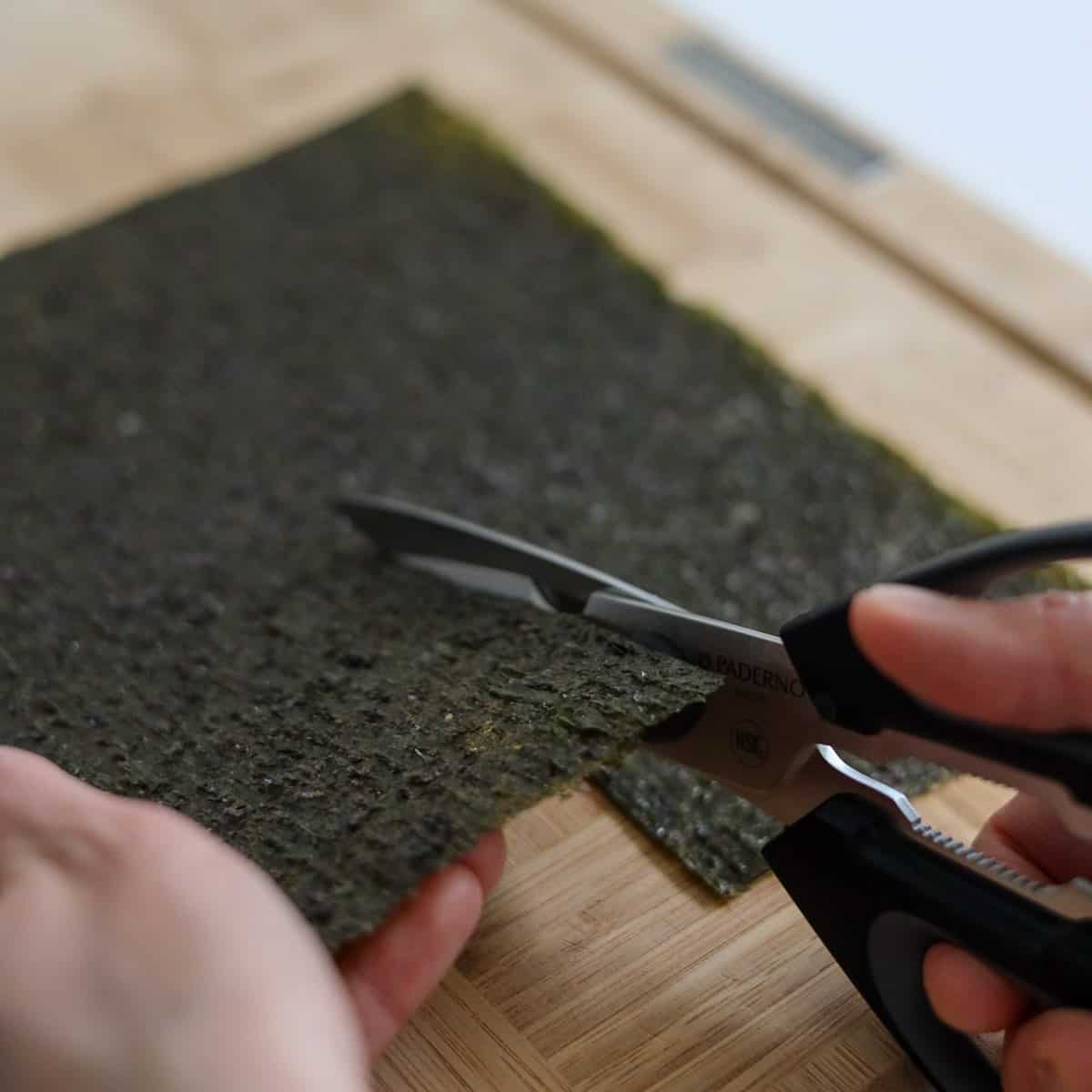 Place a sheet of nori rough side up vertically facing you. Using clean scissor a vertical slit halfway up the sheet. 