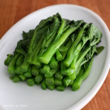 Strain the greens in a colander and then transfer to a large serving plate. Set aside.
