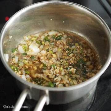 Dark brown soy sauce bubbling with translucent white and green onions.