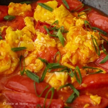 Add the cooked eggs and gently fold them into the sauce and tomatoes. Remove the pan from the heat source. Garnish with the remaining green onions.  Serve and enjoy with steamed rice or noodles!