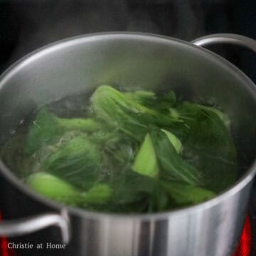 In a large pot filled with enough water, bring it to a boil on high heat. Blanch the bok choy for 1-2 minutes until softened and vibrant green. Strain in a colander and divide between four serving bowls. 