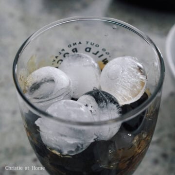 Syrup-coated black grass jelly cubes topped with clear ice cubes at the bottom of a tall glass.