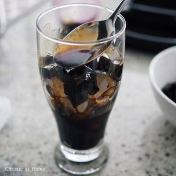 Caramel-colored streaks of brown sugar syrup running down the inside walls of a glass filled with grass jelly and ice.
