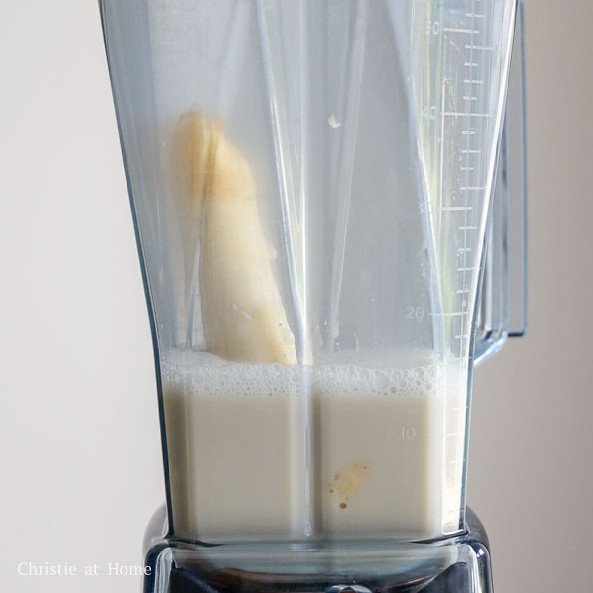 In a blender, add a peeled banana, sugar, vanilla extract and milk.