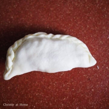 Fill the center of the wrapper with 1 tablespoon of the filling. Fold the wrapper over the filling. Pinch the edges until fully sealed. Then roll and pleat the edges using your thumb and index finger. Repeat this process until you have 26 curry puffs in total. 