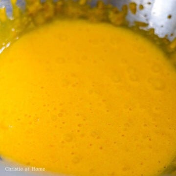 In a large mixing bowl, add egg yolks and white granulated sugar. Beat everything together until it turns pale yellow.