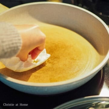 In a 10-inch pan set over medium-low heat, lightly grease it with butter using a clean paper towel. 