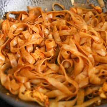 Add remaining vegetable oil into the empty space of the pan. Toss in rice noodles with noodle sauce mixing everything together. Taste test the noodles and if they are not al dente,  add 2-4 tablespoons of water and cook until they become soft and chewy. If you're using a steel wok, let the noodles sit in the pan undisturbed so they can slightly char for a smoky flavor. 