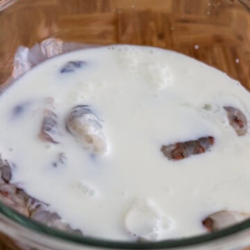 Shrimp soaking in a bowl of buttermilk to tenderize.
