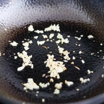 Minced garlic sizzling in shimmering hot oil.