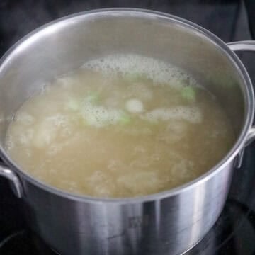 Combine chicken stock and scallion whites in a medium pot.