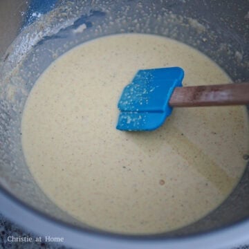 Whisking a pale, smooth wet starch batter in a large glass bowl.