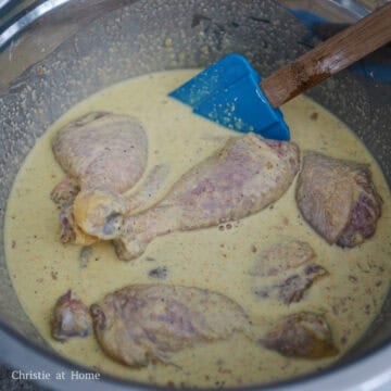 Raw chicken drumsticks being submerged and coated in a thick wet batter.