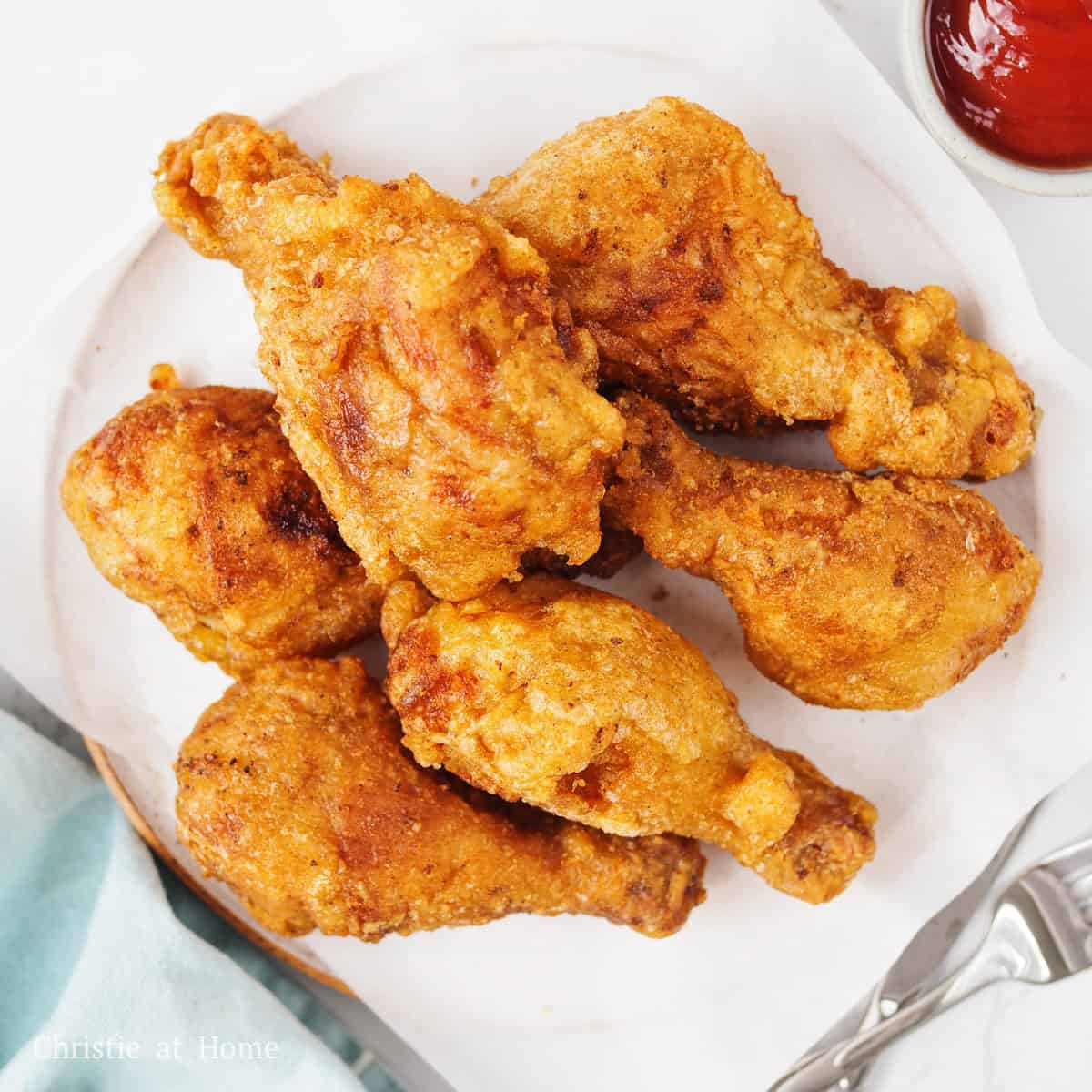Golden brown fried chicken drumsticks resting on a serving plate.