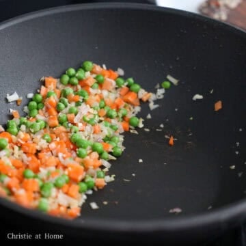 Fry garlic and shallots for 10 seconds or until softened. Quickly add in green peas and carrots and fry for another 10 seconds. Push everything to the side of the wok.