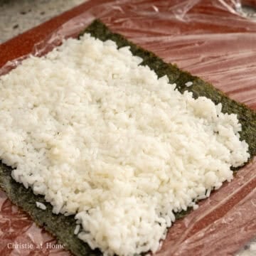 On a bamboo mat or sushi mat (or plastic wrap set on a cutting board), place your a sheet of nori horizontally rough side up, shiny side down. Evenly spread 1 cup of seasoned rice leaving a ½ inch border at the ends. 