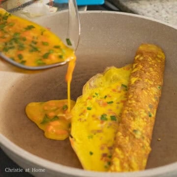 Push the egg roll to the midway point of the pan, then fill the pan again with another thin layer of the egg mixture to the round side of the egg pancake. Cook this layer until the edges lift away from the pan.