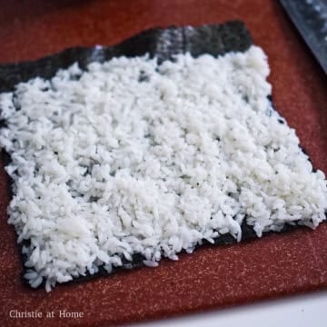 On a clean working surface, lay out a sheet of gim or nori in a vertical position. Spread about ¾ cup of seasoned rice on your sheet leaving a 1-inch border at the end of the sheet.