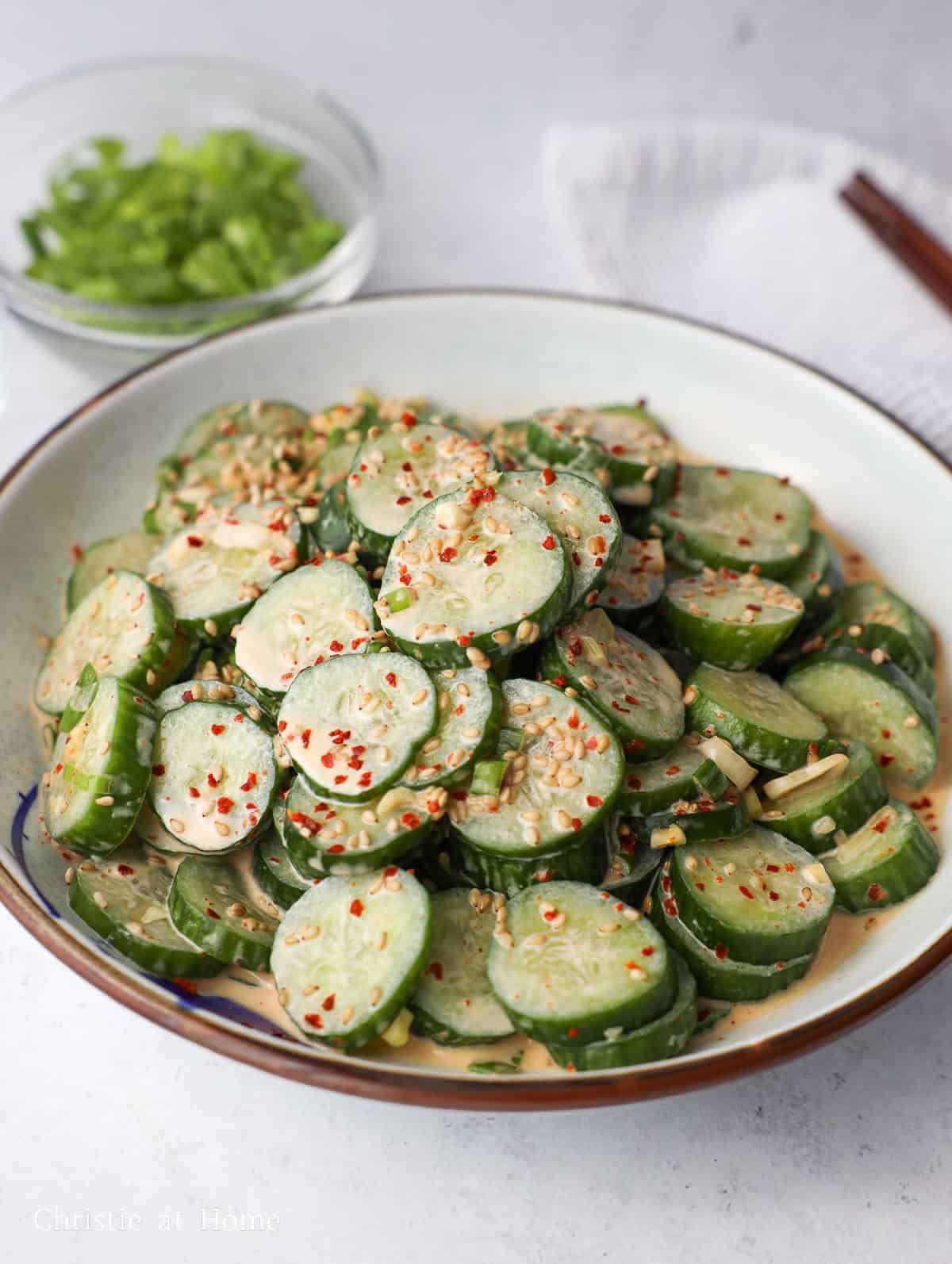 a plate of Kewpie mayo cucumber salad with sesame seeds, green onions, and gochugaru flakes